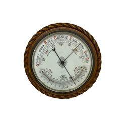 1930’s aneroid barometer with a 10” porcelain dial recording barometric air pressure from 28 to 31 inches with weather predictions, curved mercury thermometer, steel indicating hand and brass recording hand, oak case with carved rope work decoration.