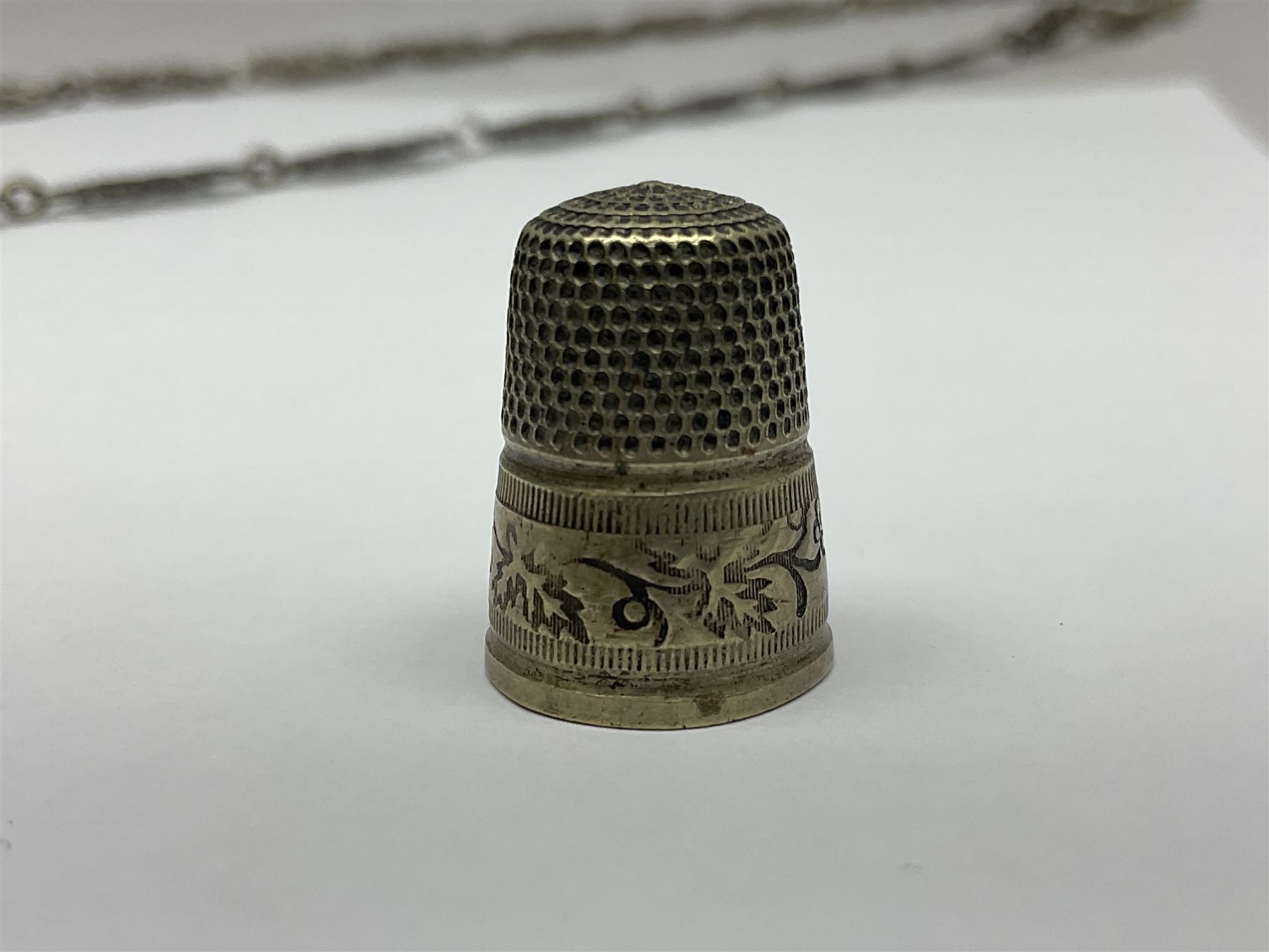 19th century continental silver plated chatelaine, the main body flanked with winged mythical beasts and central soldier slaying a dragon supporting three suspended items to include velvet lined small basket and long clasped filigree chain, together with a thimble