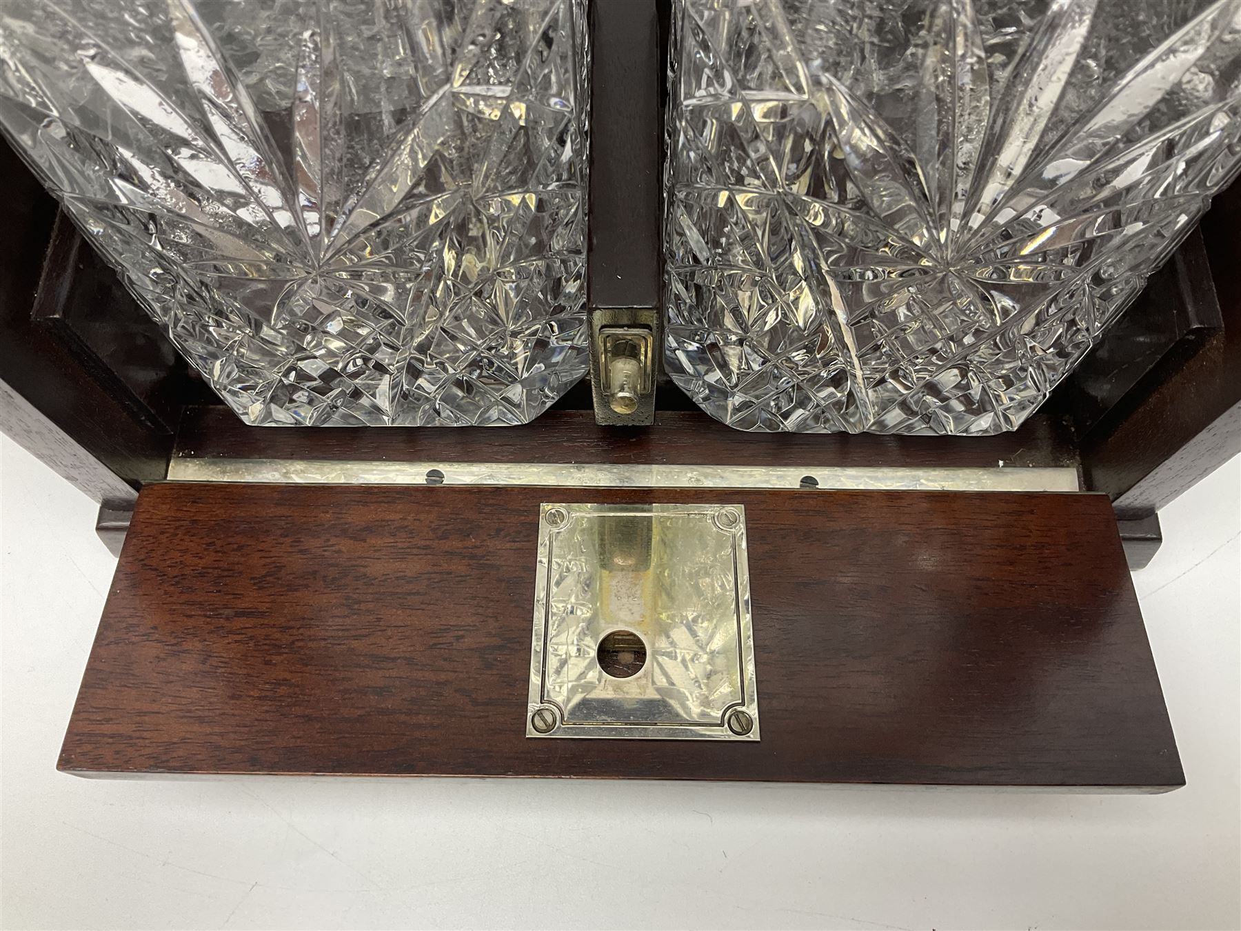 20th century mahogany tantalus with plated mounts and handle, with two recesses containing two square sided cut glass decanters, with key, including handle H36cm W27cm