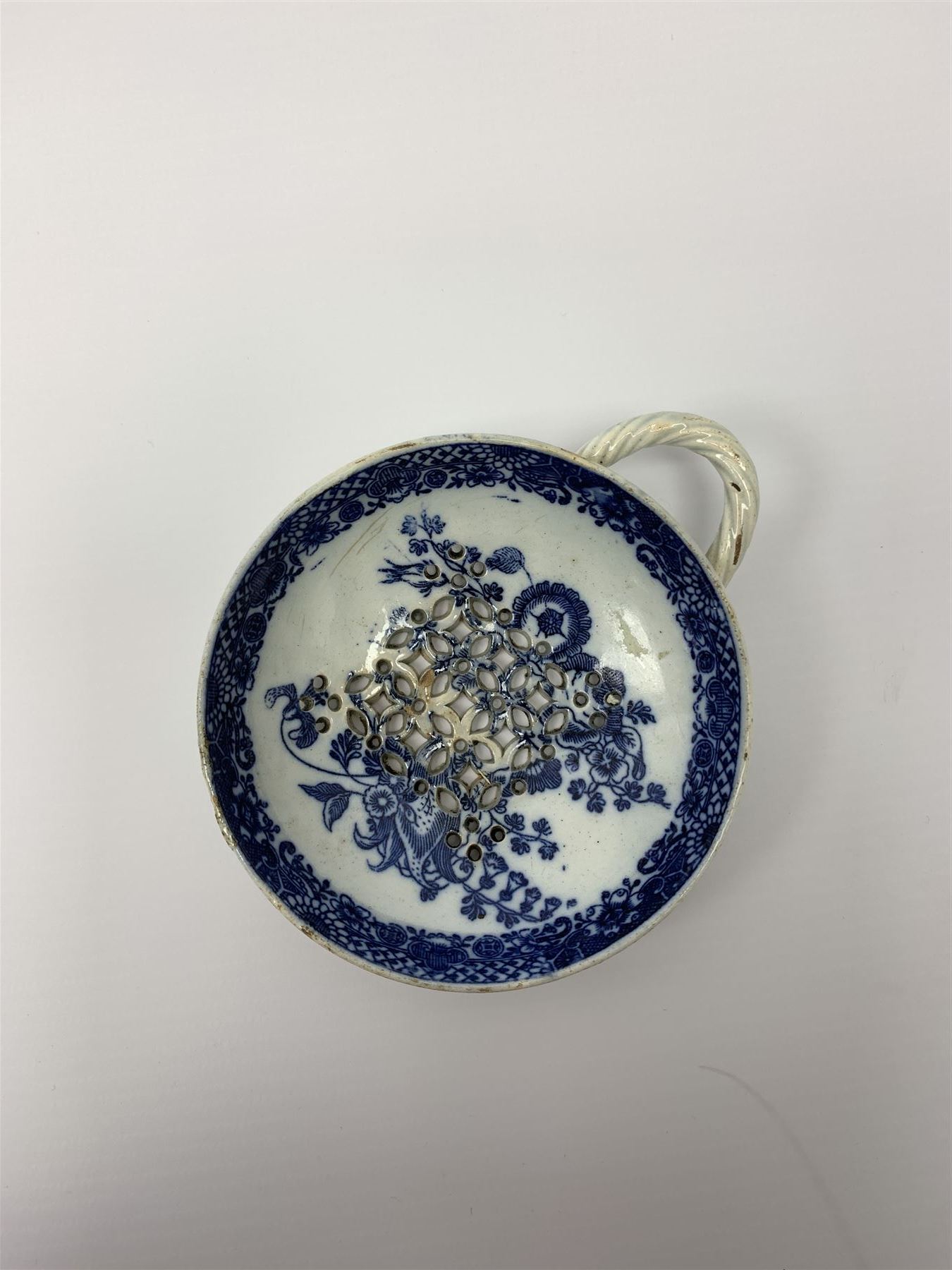 Late 18th/early 19th century Leeds Pottery egg drainer, the pierced bowl of circular form decorated with blue transfer printed floral spray and floral border, the twisted handle with foliate mounts, bowl D9cm