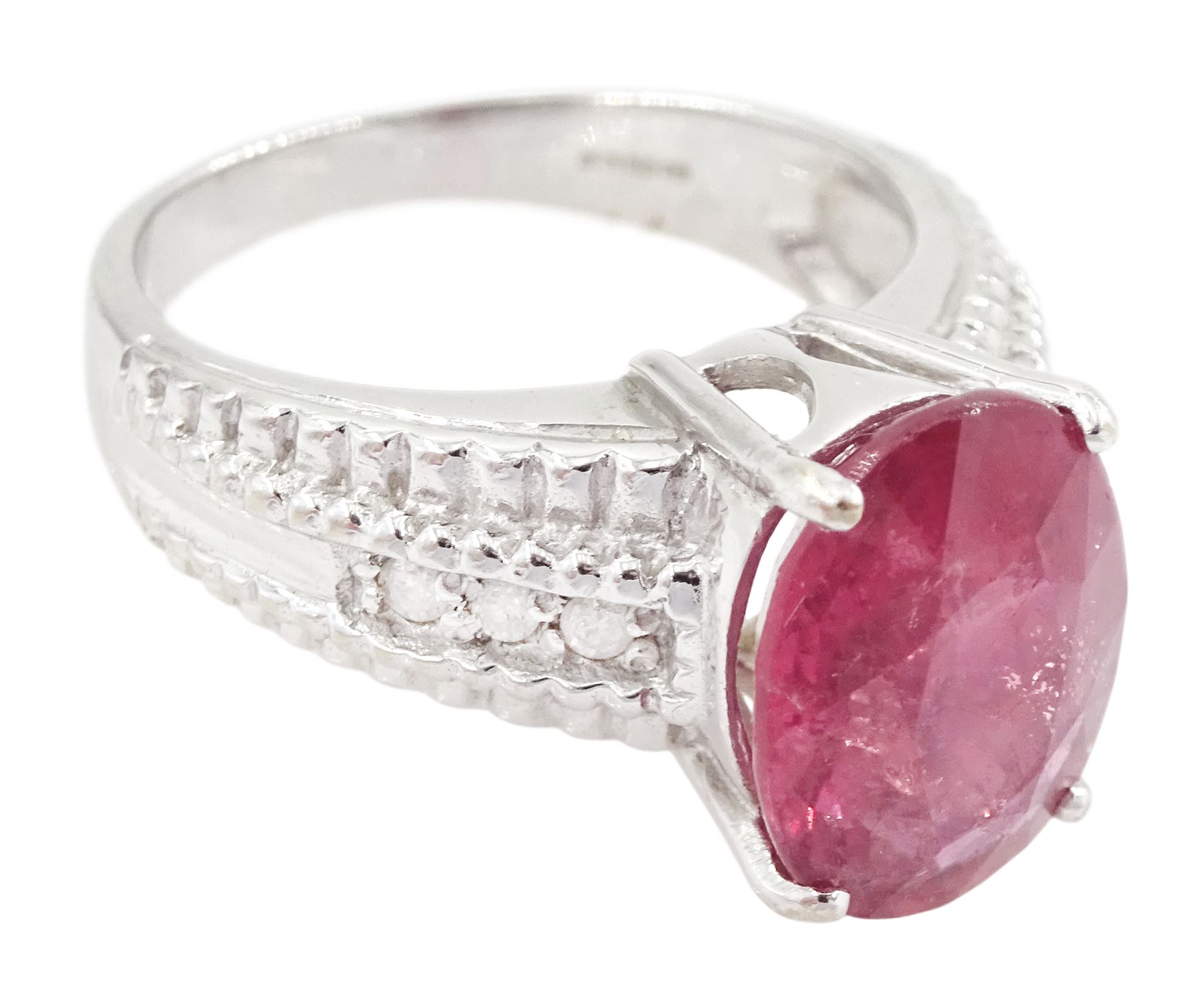 18ct white gold ruby and diamond ring, single oval cut ruby of approx 5.05 carat, with three round brilliant cut diamonds to each shoulder, Birmingham 2006