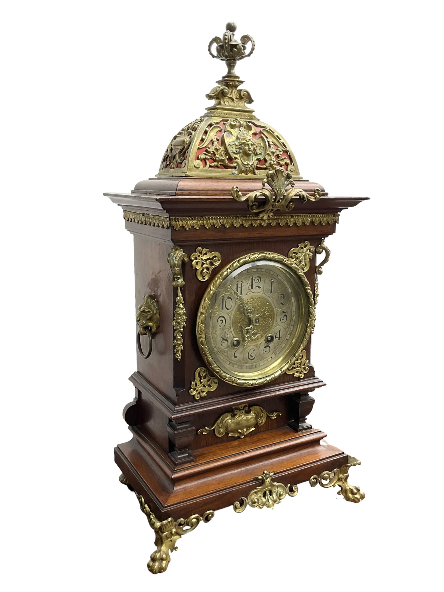 Lenzkirch - Edwardian German 8-day  mantle clock in an oak case with brass mounts and a pierced dome pediment with finial, silvered dial with Arabic numerals, gilt hands and dial centre, rack striking movement, striking the hours and half-hours on a coiled gong. With pendulum and key.