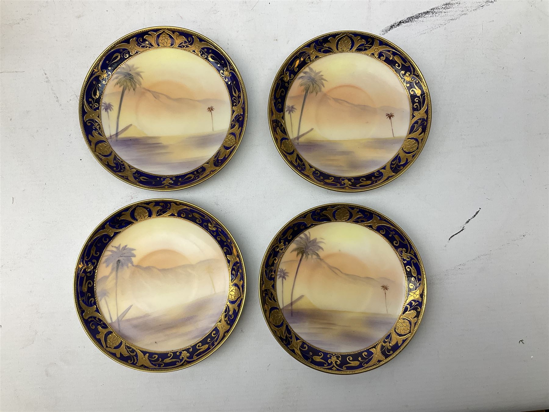 Noritake tea service for four, decorated with desert camel scene with blue border and gilding, comprising four teacups and saucers, four side plates, lidded sucrier, teapot and jug, together with twin handled pedestal bowl etc (19 pcs) 