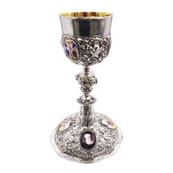 German silver chalice, the bowl, stem and foot each with 19th century repousse and chased decoration depicting putti masks, C scrolls and flowers, set with two hand painted porcelain roundels, possibly Berlin, and six later applied enamel roundels, each depicting religious scenes, the gilded bowl upon knopped stem and spreading octofoil foot, the base with marks for Munich, c.1695 and maker's mark FK