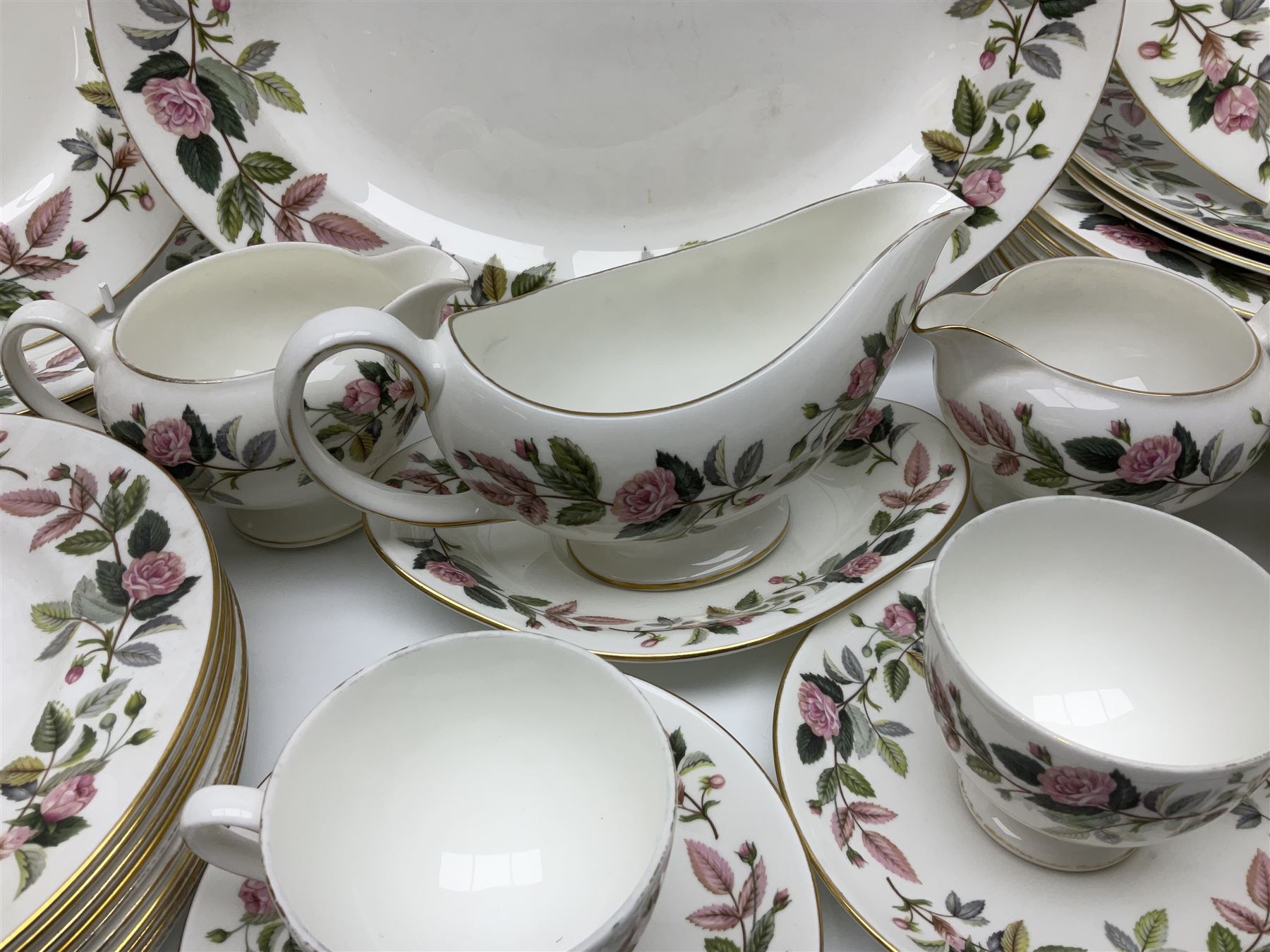 Wedgwood Hathaway Rose pattern tea and dinner wares, comprising twelve saucers, sixteen teacups, twenty tea plates, jug, sucrier, thirteen shallow bowls, sauce boat and saucer, two lidded tureens, larger jug, ten dinner plates, nine smaller plates and two large oval serving dishes
