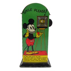 Saalheimer & Strauss Germany 'Smile Please' Mickey Mouse mechanical tin-plate money bank, Type I, depicting Mickey posing with folded hands on the front and as a photographer with a camera tripod on the reverse along with the motto 'If you only pull my ear you will see my tongue appear. Place a coin upon my tongue save your money while you're young'. H17.5cm