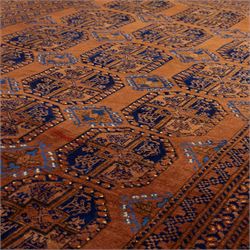 Pakistani Bokhara hand-knotted carpet, camel field decorated with rows of large tekke style octagonal guls enclosing stylized geometric motifs, interspersed with small stepped diamond devices within multiple geometric borders, with fringe ends 