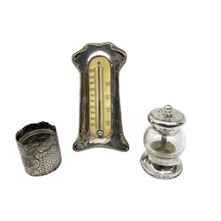 Group of silver, comprising silver mounted Art Nouveau desk thermometer, hallmarked J & R Griffin (Joseph & Richard Griffin), Chester 1906, silver mounted and glass pepper grinder, hallmarked John Grinsell & Sons, London 1899, embossed case of cylindrical form with later glass liner, hallmarked Arthur Willmore Pennington, Birmingham 1902, napkin ring with engraved scroll decoration, hallmarked Birmingham, date letter and makers mark worn and indistinct, money clip stamped 925, teaspoon marked Sterling, and Continental pickle fork marked 8305. 