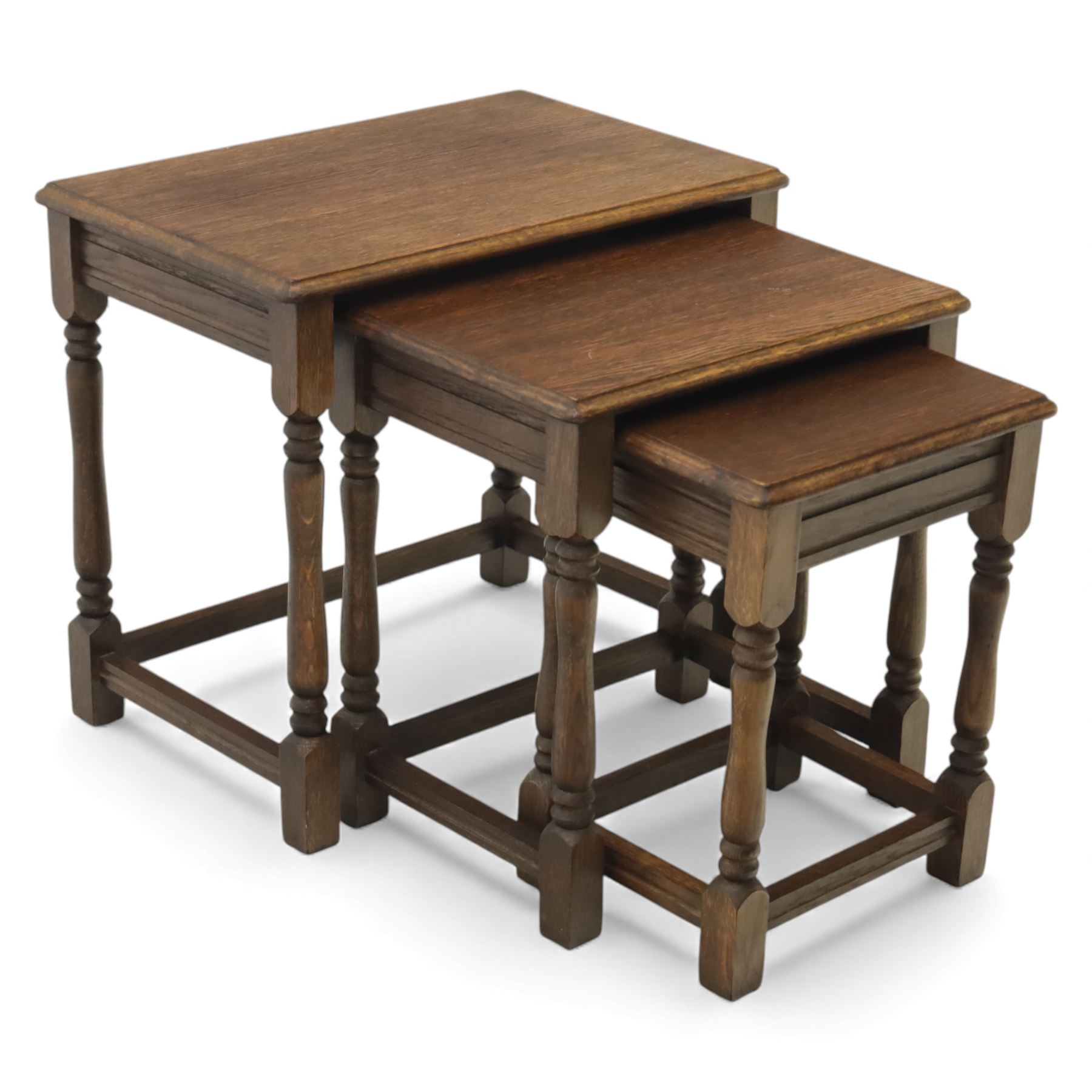 Nest of three dark oak tables, rectangular top with turned supports, tables suspended on rails