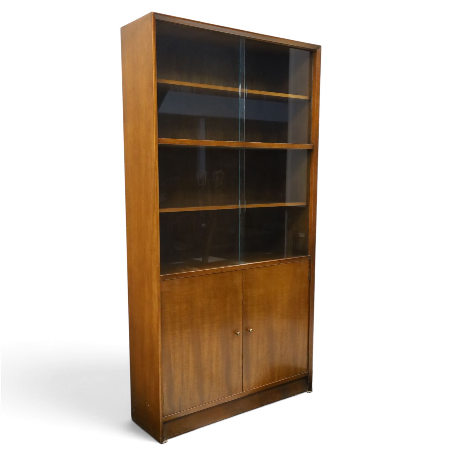 Herbert E Gibbs - Mid 20th century teak glazed bookcase cabinet, rectangular form with two sliding glazed doors enclosing adjustable shelves, lower cupboard enclosed by twin doors and fitted with internal shelf, on plinth base