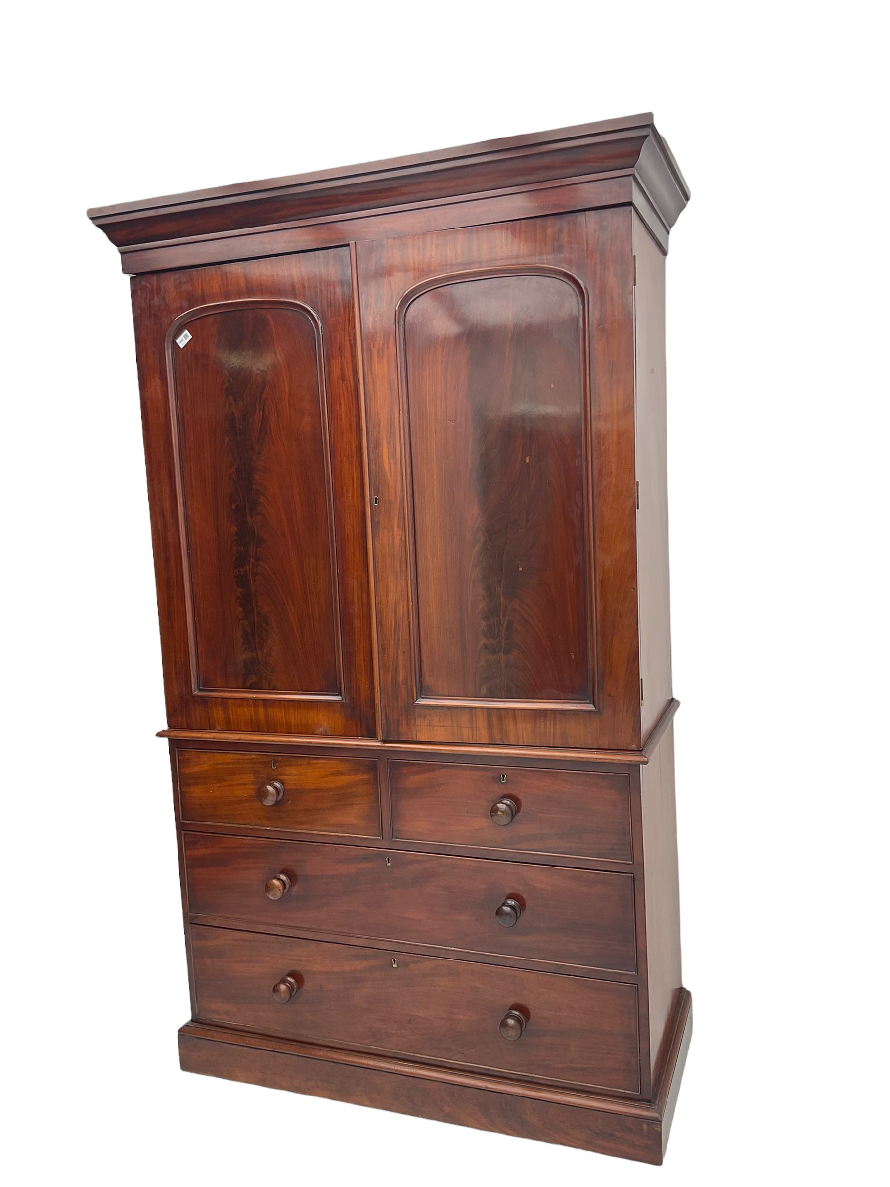 Victorian mahogany linen press, projecting moulded cornice, two doors with arched panels enclosed four linen slides, the lower section fitted with two short and two long drawers, on plinth base
