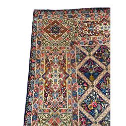 Persian Kirman indigo ground carpet, the field with repeating lozenge tiles with overall floral decoration, the main border with floral panels enclosed by the guards