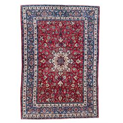 Persian red ground rug, the central ivory pole medallion surrounded by scrolling interlaced foliate patterns, the guarded indigo border with repeating palmette motifs