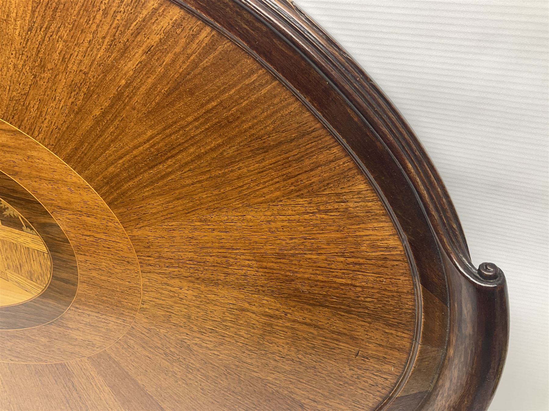 Late 19th/early 20th century mahogany and marquetry inlaid tray, of oval form with twin scrolled handles and moulded border, the central panel inlaid with figures seated at a table drinking tea, L99cm