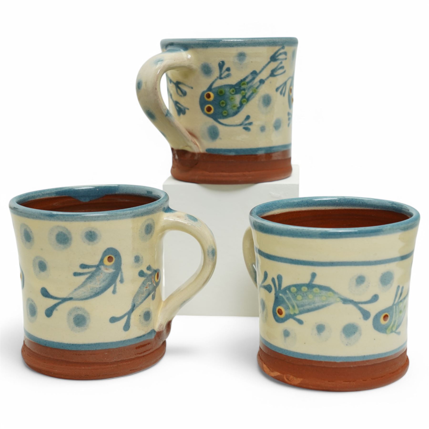 Coxwold studio pottery charger, decorated in a blue and yellow glaze with swimming frogs, together with three mugs with similar swimming fish and frogs, each painted or impressed mark, charger D33cm (4)