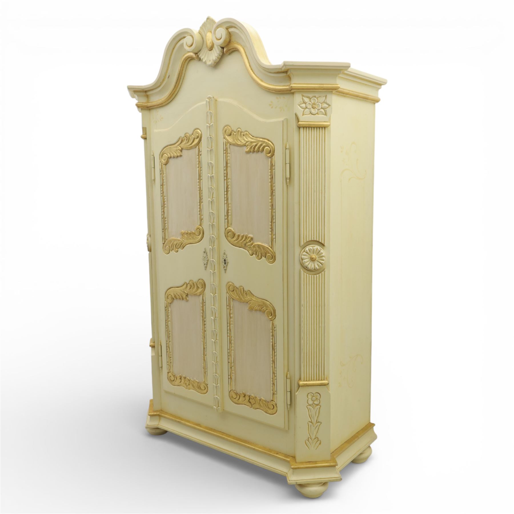 20th century French white and parcel gilt painted armoire, the shaped and scroll moulded cornice centred with a stylised foliate, the double doors with raised panel reserves applied with gilt foliate scrollwork, flanked by fluted pilasters with floral capitals, opening to a fitted interior with shelving and hanging space, raised on a moulded plinth on squat bun feet