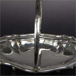 Early 20th century silver swing handled basket, of oval form with shaped rim and upon four bun feet, hallmarked C W Fletcher & Son Ltd, London 1918