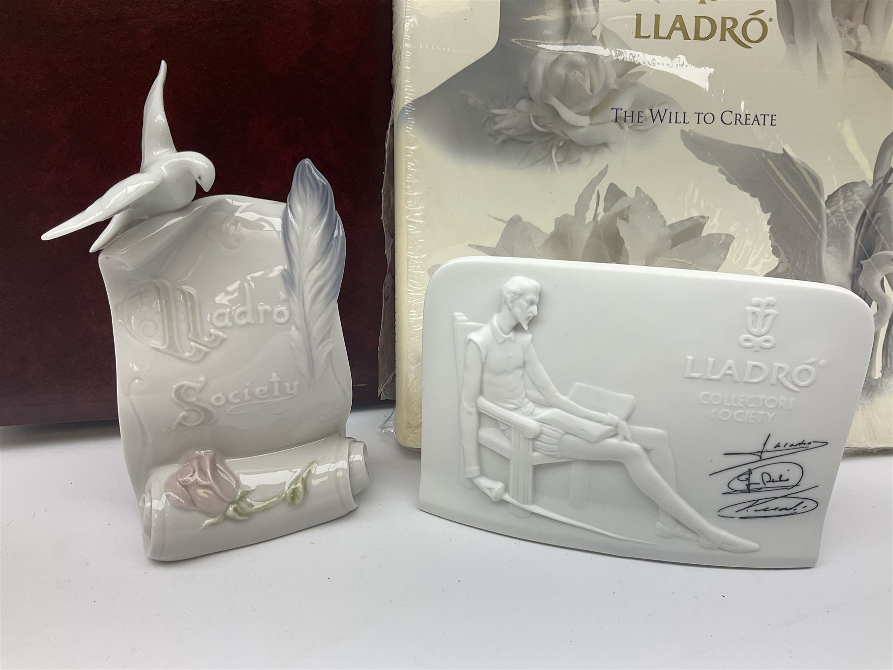 Lladro Collectors Society items, comprising of The Will to Create book, two candle holders; Sailing the Sea no 17665, Dolphins at Play no 17666, Plaque Bringing Us Together, key fob, leather wallet and a members joining pack with plaque, all in original boxes  