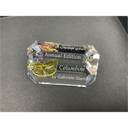 Swarovski Crystal Masquerade trilogy; 1999 Masquerade Pierrot, 2000 Columbine, 2001 Harlequin all with accompanying plaque, stand and original box, together with a glass display case with mirrored back and sides 