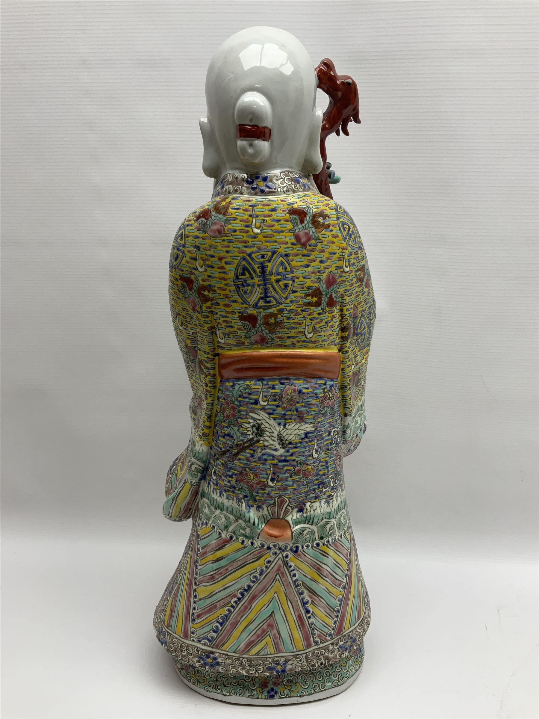 Chinese Republic Period porcelain figure, modelled as Shoulao, wearing elaborately enamelled robes decorated with peaches and flower heads, with impressed mark beneath, H55cm