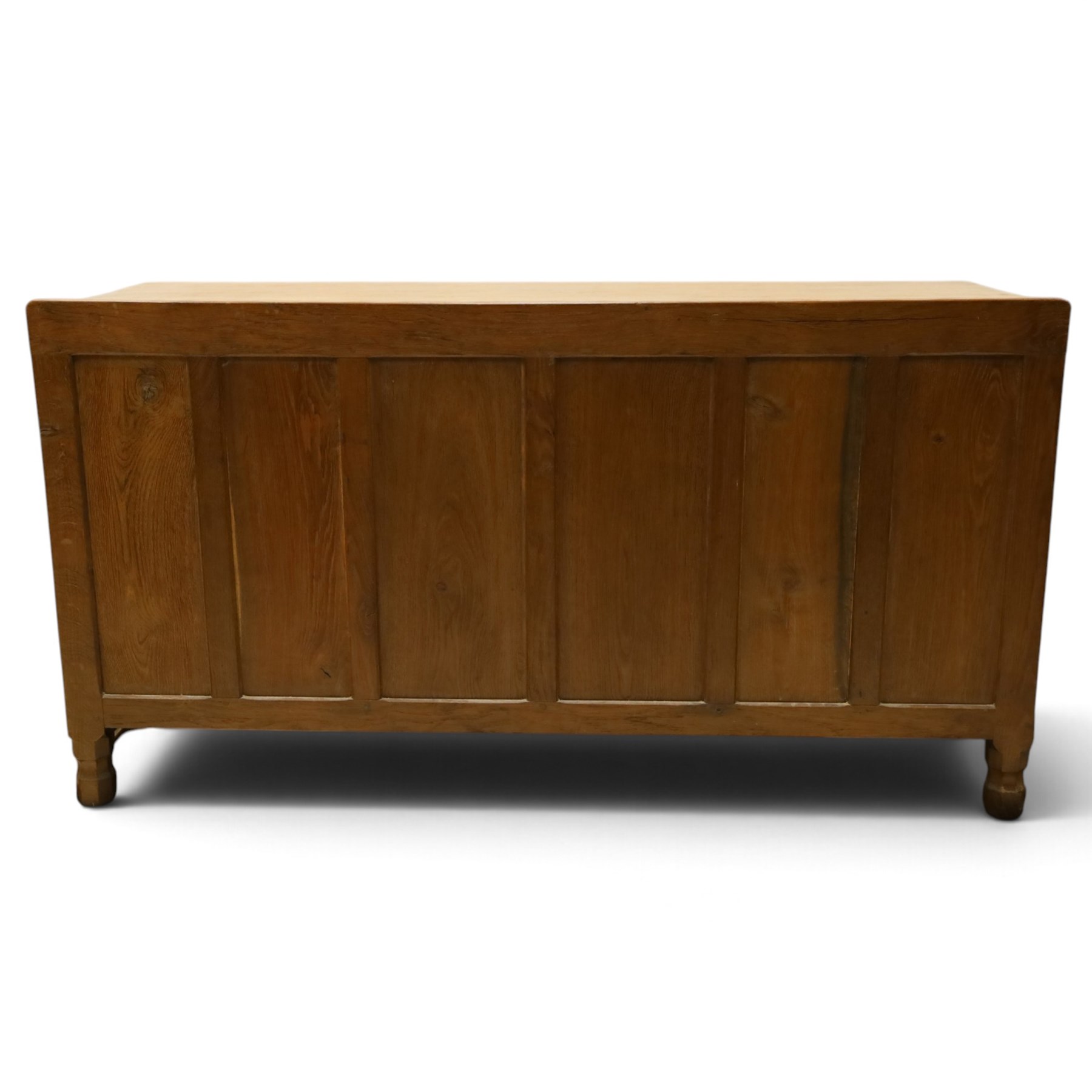 Mouseman - adzed oak kneehole dressing table or desk, the rectangular adzed top with raised back and canted corners, over an arched recessed kneehole flanked by three graduating drawers to each side with turned knob handles, raised on octagonal feet, with carved mouse signature, by the workshop of Robert Thompson of Kilburn