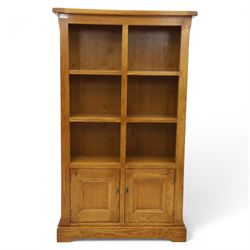 Old Charm - 'Chatsworth' light oak bookcase with two cupboards, featuring two fixed horizontal shelves forming six  rectangular open compartments, over twin panelled cupboard doors, chamfered uprights and plinth base