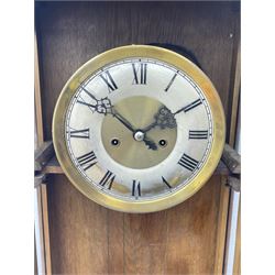 Early 20th century oak cased wall clock, the door glazed with circular convex dial glass and bevelled upright panes, circular brass and silvered Roman dial, twin train driven movement striking on coil 