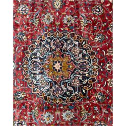 Northwestern Persian Lillihan hand-knotted carpet, madder red field with scrolling vines, rosettes, and palmettes around a central circular medallion in navy, ivory and ochre, and ivory ground spandrels within a navy border of stylized flowerheads and vines between multiple guard stripes 