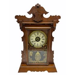 An early 20th century spring driven alarm clock in the style of an American  “gingerbread” shelf clock, rectangular wooden case with applied incised mouldings on a shaped taper foot plinth, full length glazed door with flowers and leaves, visible gilt pendulum bob, with a painted white metal dial inscribed “Fattorini & Sons Patent Automatic Alarm”, roman numerals and minute track with brass alarm setting disc, steel spade hands, spun brass bezel with winding apertures, alarm sounding on both a coiled gong and bell, two advertising/trade labels pasted to the case backboard.