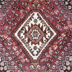 Southwestern Persian Qashqai rug, central diamond medallion with hooked motifs flanked by four corner medallions on a rich red madder field with dark brown ground of stylized floral and animal motifs, and ivory border with alternating floral palmettes and a red main  border with a meandering vine pattern 