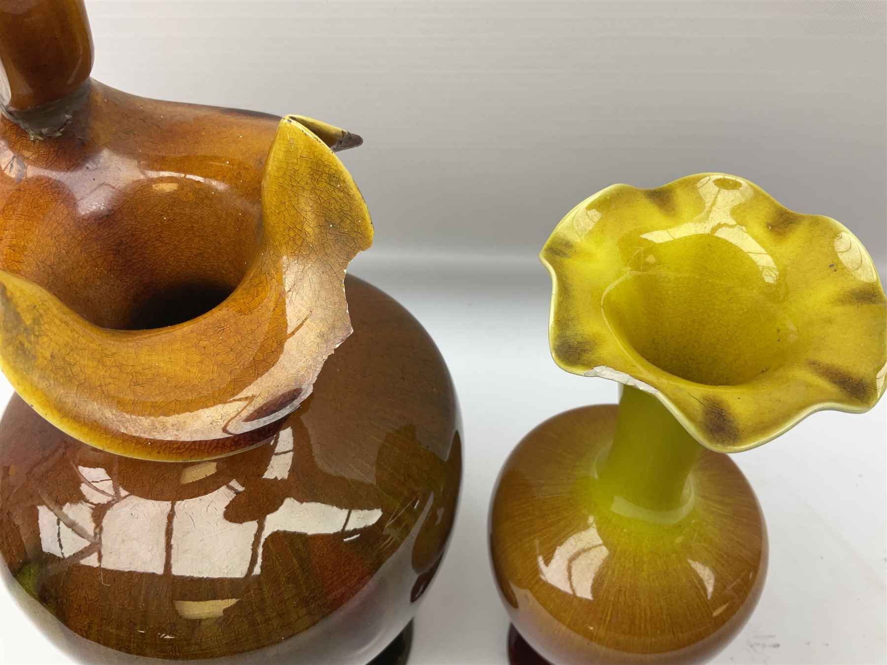 Linthorpe pottery vase with crimped rim and ovoid body, Linthorpe jug with high loop handle and crimped spout, a pair of candlesticks with a green, brown glaze and other similar pottery 