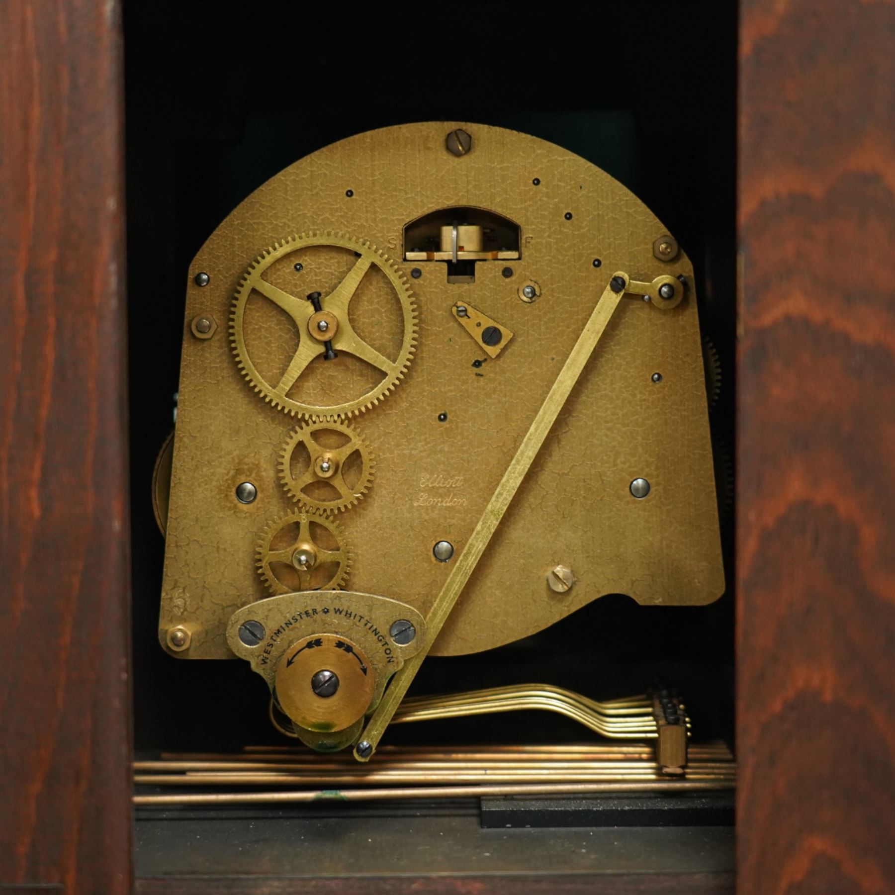 Carmichaels of Hull - mahogany cased 8-day musical grandmother clock c 1930 - with an arched pediment and arched hood, full-length trunk door on a short plinth raised on bracket feet, brass dial signed Tempus Fugit and Carmichaels of Hull with cast spandrels, matted dial centre and silvered chapter with Roman numerals, three train spring-driven movement chiming the quarters and hours on 8 gong rods with Westminster or Whittington chimes, movement stamped Elliott London with pendulum.