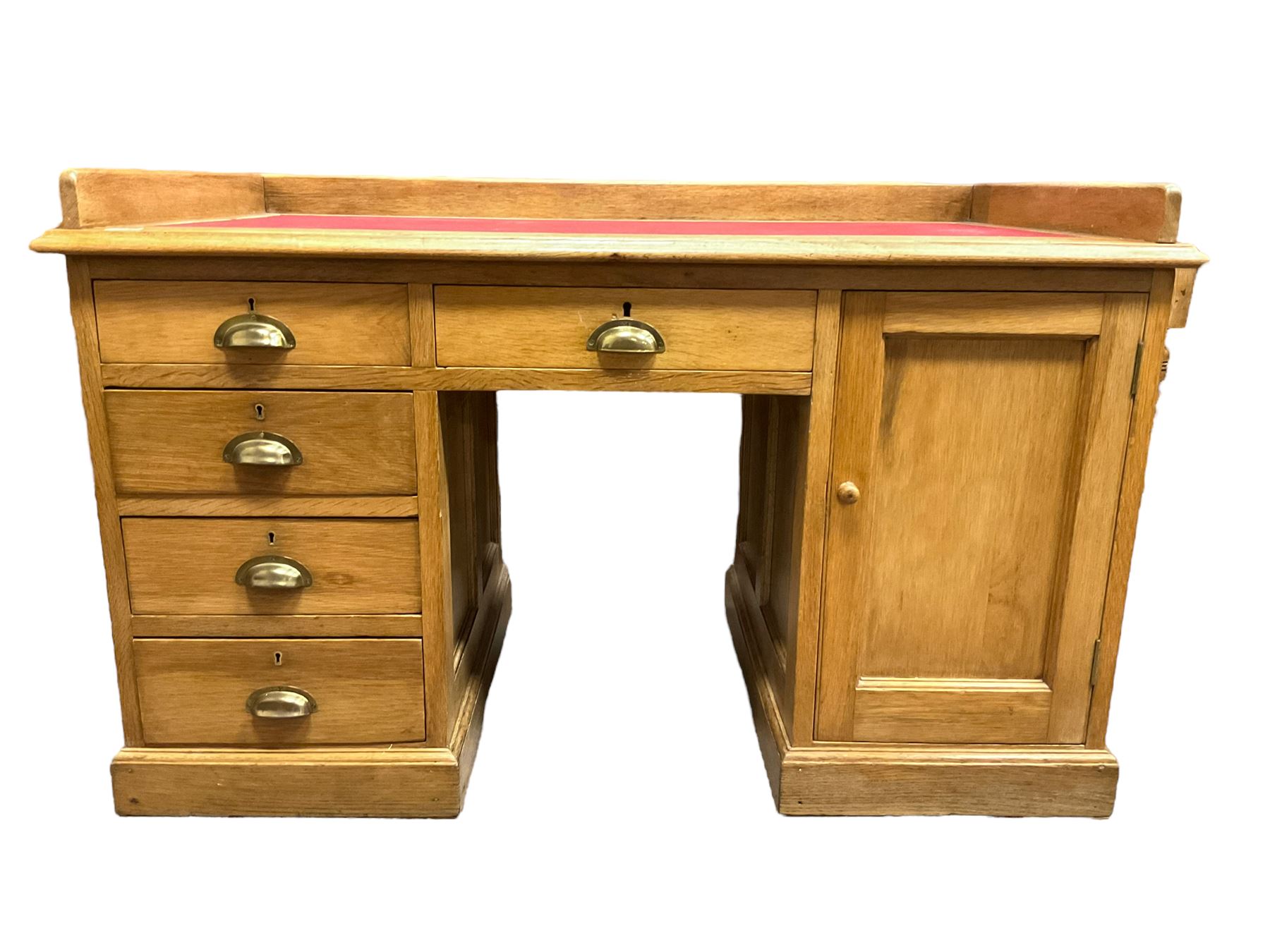 Early 20th century oak ‘Headmasters’ twin pedestal desk, three-quarter raised gallery back and inset leather writing surface, fitted with central drawer flanked by four graduating drawers and single cupboard