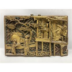 Two carved oriental wall hangings, the first example gilded depicting a temple and garden scene, the second figures in a garden, L49cm