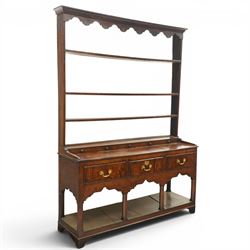 18th century Georgian oak dresser base with plate rack, the three-tier plate rack with shaped frieze, the base with rectangular top with raised back fitted with five spice drawers, over three drawers with brass swan neck handles, raised on six square chamfered supports united by undertier 