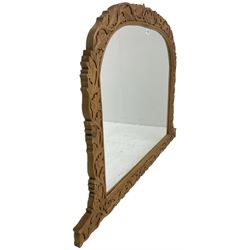 Arched pine overmantel mirror, the frame carved with trailing foliage, moulded inner slip with plain mirror plate