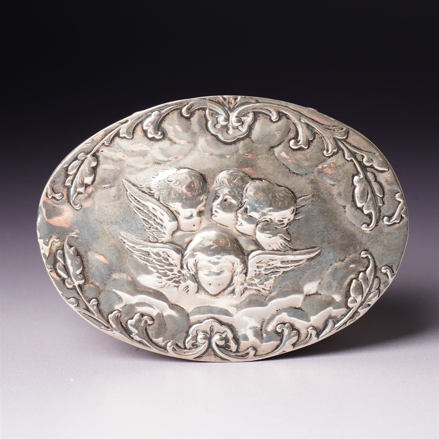 Edwardian silver oval dressing table box, the hinged cover embossed with angel heads W10cm London 1902 Maker William Comyns & Sons and an Edwardisn pierced silver oval sweetmeat basket L18cm Sheffield 1907 Maker James Dixon & Sons Ltd