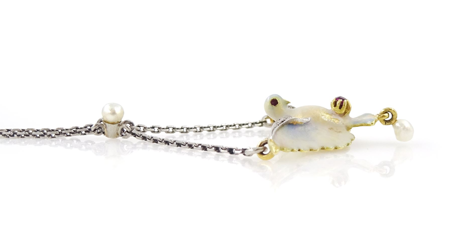 Early 20th century platinum and gold enamel, pearl and diamond dove pendant necklace, the dove in flight, with applied opalescent enamel, ruby set eyes and the wings outlined with rose cut diamonds, its claws holding a round cut ruby and suspending a pearl drop, stamped 18ct, to a platinum chain set with an additional pearl