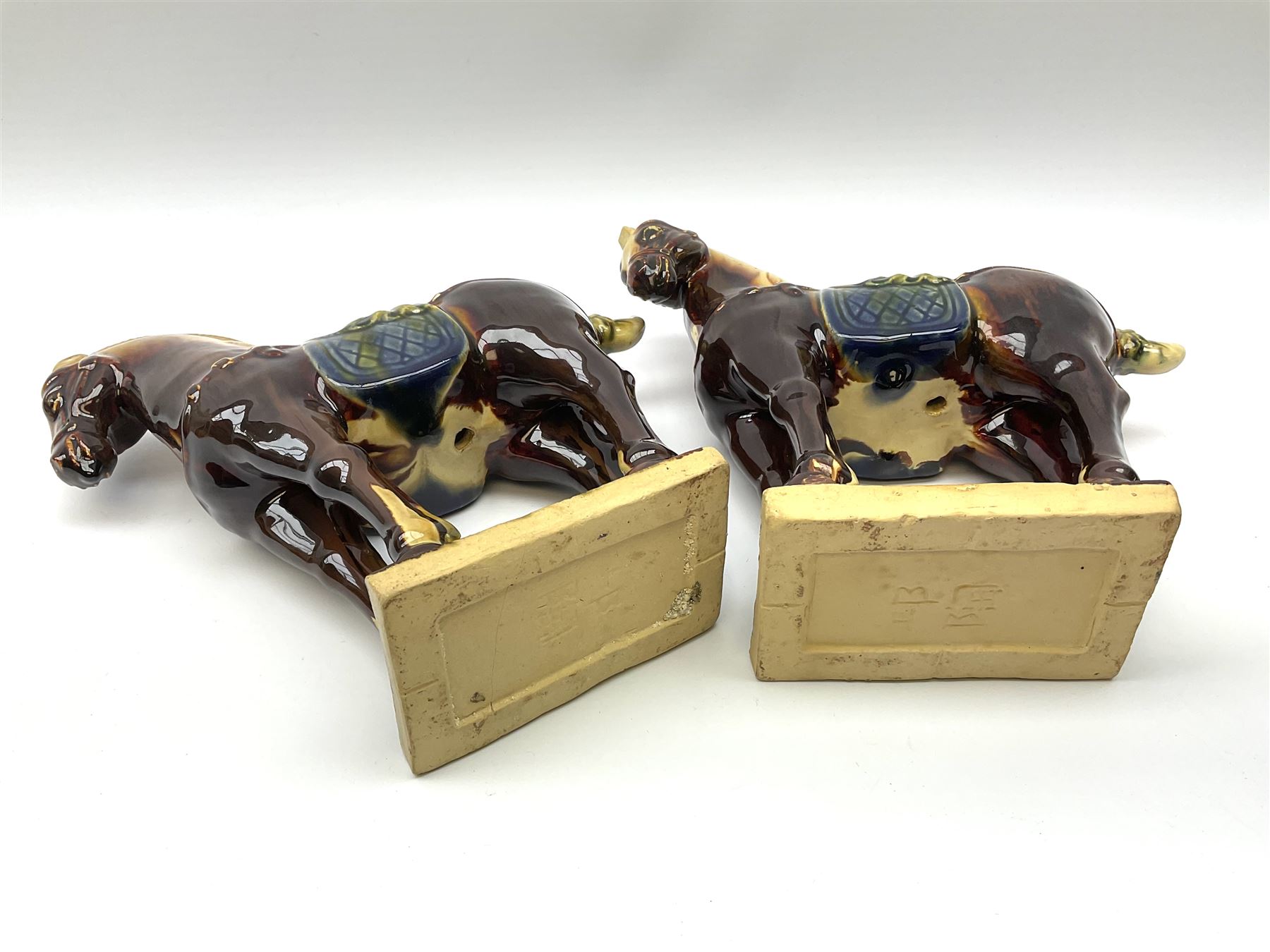 A pair of glazed pottery Tang style horses, each with impressed marks beneath, each approximately H25.5cm. 