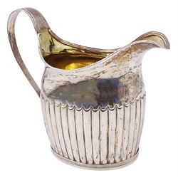 Large George III silver cream jug, of part fluted oval-helmet form, with engraved crest beneath lip, curved handle, and gilt interior, hallmarked William Bateman I, London 1816, including handle H4.5cm, approximate weight 11.20 ozt (348.6 grams)