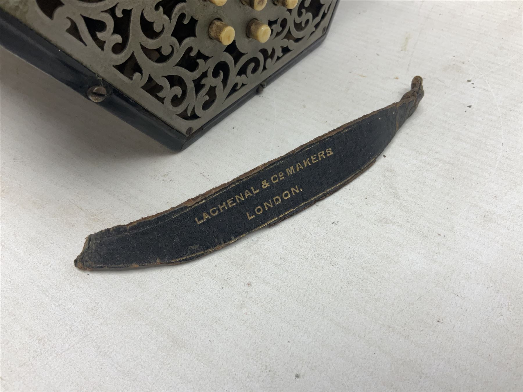 19th century Lachenal concertina of hexagonal form with fretworked nickel ends and thirty-four plus one bone buttons; straps marked Lachenal & Co Makers London and wooden handle stamped English Make Trade Mark L16cm