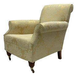 Traditionally shaped hardwood-framed armchair, rolled back and arms, upholstered in pale gold and cream damask fabric with repeating foliate pattern, on turned feet with brass cups and castors