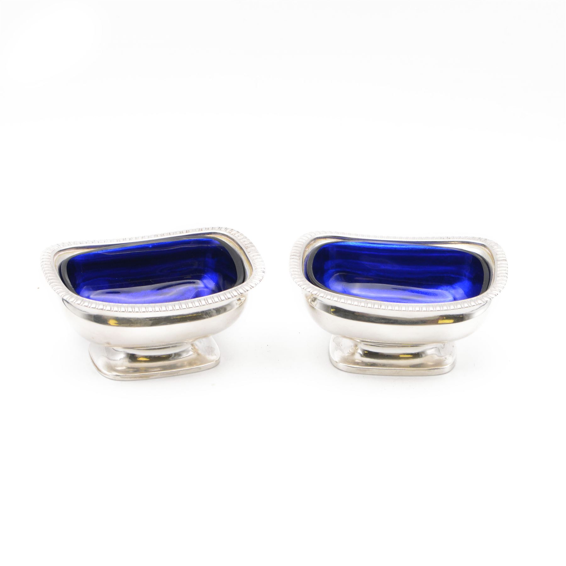 Pair of George III silver open salts, of rectangular form with gadrooned rim and upon a rectangular base, hallmarked J E Terrey & Co, London 1818, with blue glass liners, H4.5cm