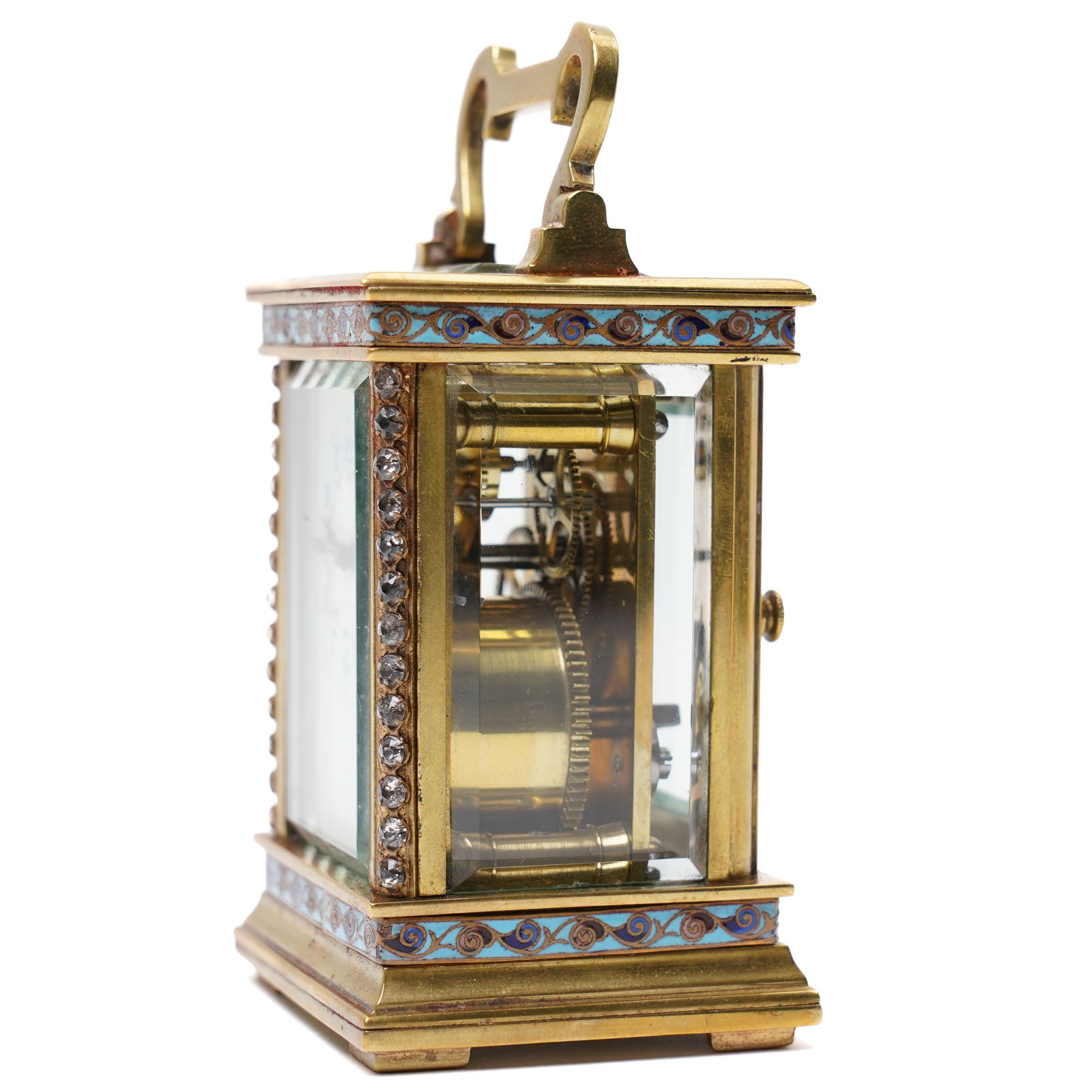 French- Edwardian miniature brass 8-day timepiece carriage clock with cloisonné panels to both base and cornice and paste gems to the front columns, decorative porcelain dial with a floral swag, blue Arabic numerals, minute track and pieced steel hands, square viewing glass to the top with a silvered lever escapement, with original leather bound traveling case.