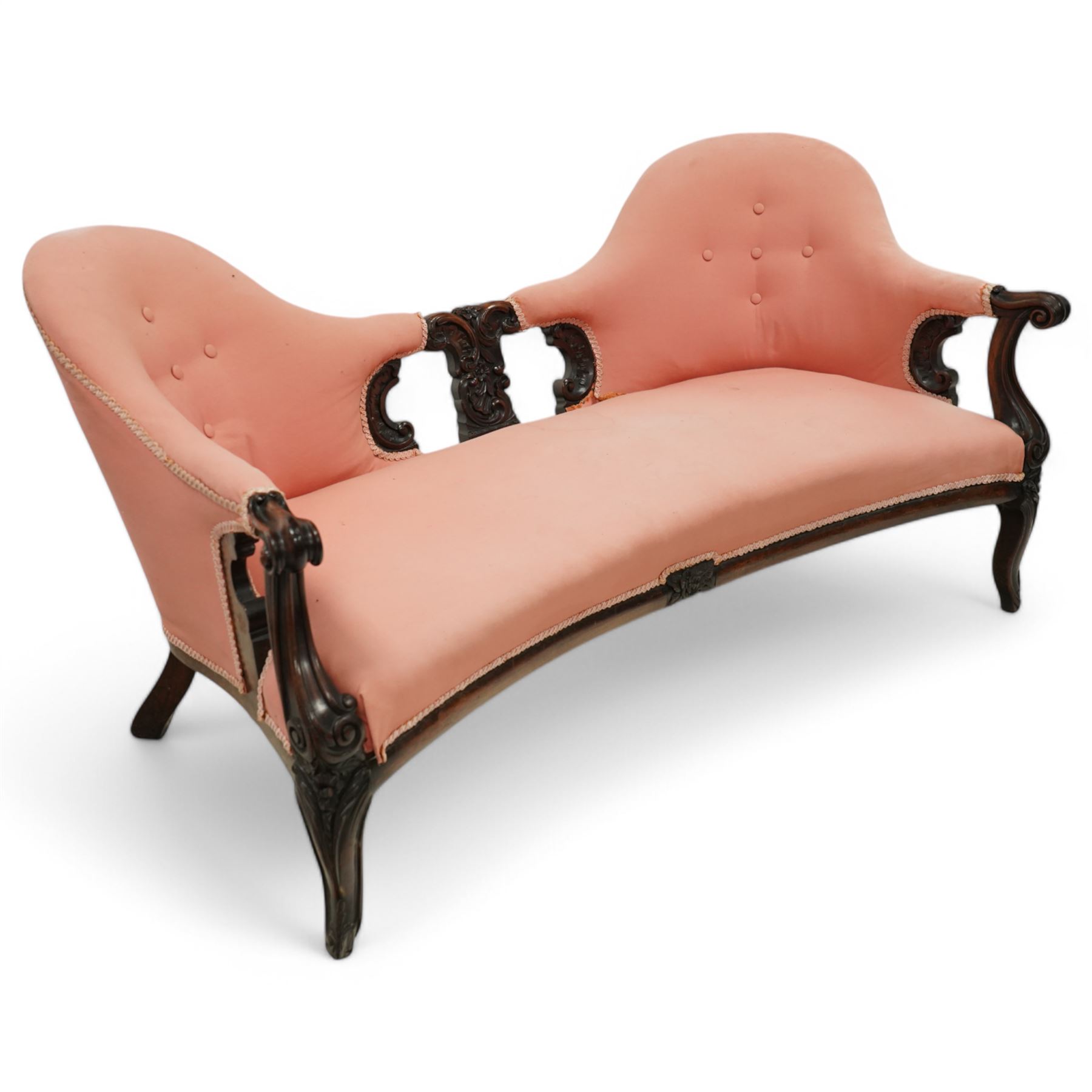 Mid-19th century carved rosewood double-ended settee, double spoon back with central splat carved with C-scrolls and shells, upholstered in pink buttoned fabric, scroll carved arm terminals on shaped supports, on leaf and flower head carved cabriole feet 