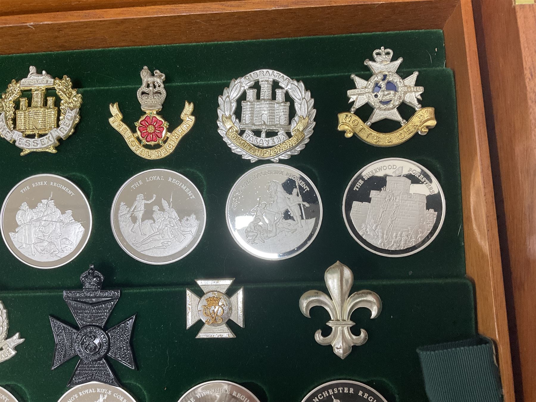 Great British Regiments, 1977, set of fifty two frosted silver medals by the Birmingham Mint, each bearing the name of a regiment with a depiction of an action on the obverse and further details on the reverse, all hallmarked Birmingham Mint, assay offices and dates; together with 52 base metal copy cap badges for each regiment, all housed and mounted on two trays and contained within a wooden presentation case, with brass plaque and fittings, lock and key, with a certificate of authenticity 