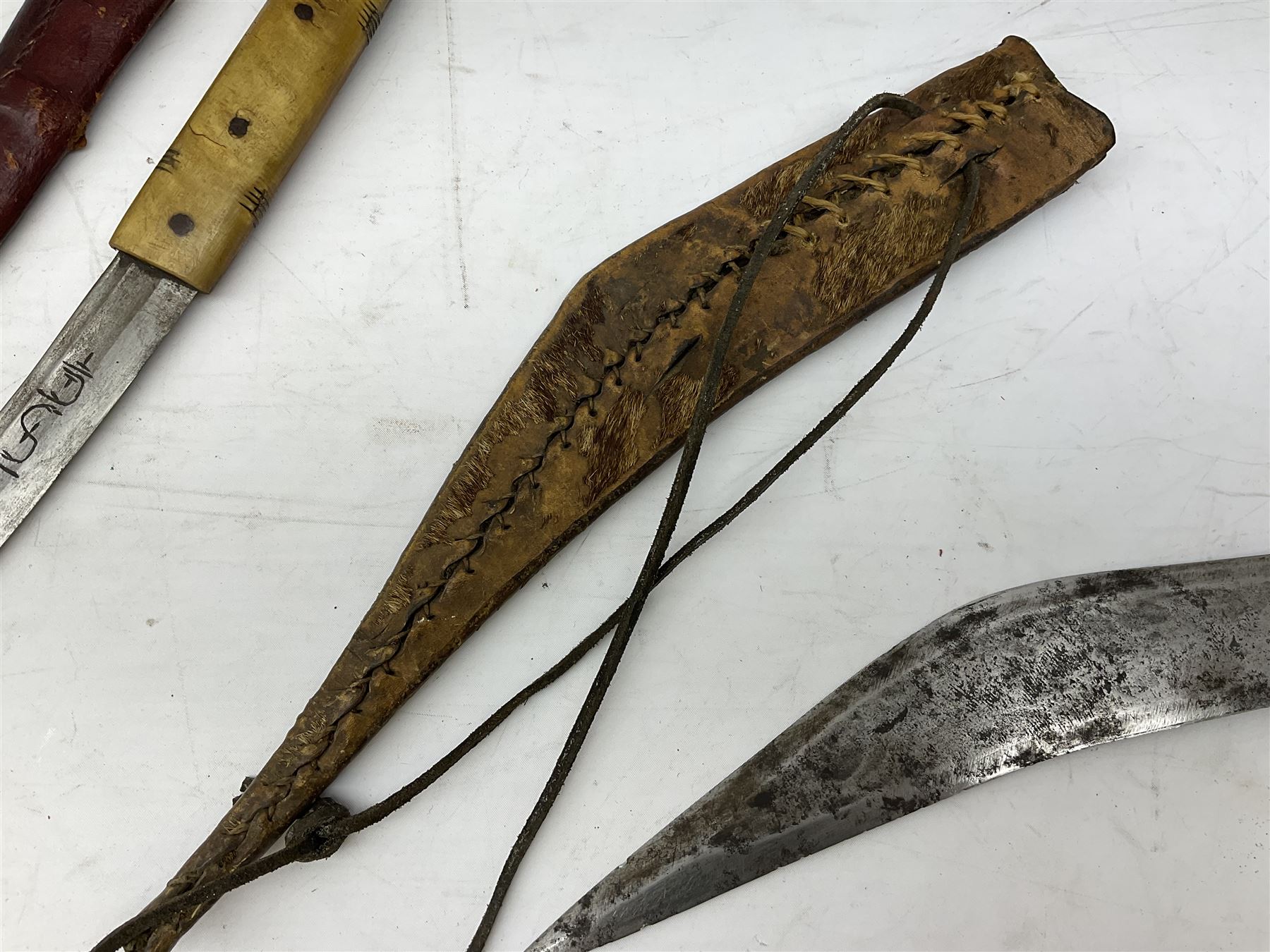 Near pair of African Moroccan Berber tribal Shula daggers each with engraved 39cm curving fullered steel blade, carved and inlaid horn grip and leather covered scabbard L57cm overall; kindjal style dagger with brass covered and jewelled grip and scabbard; another Eastern dagger with leather covered grip and scabbard; and a large Eastern knife with animal hide scabbard (5)