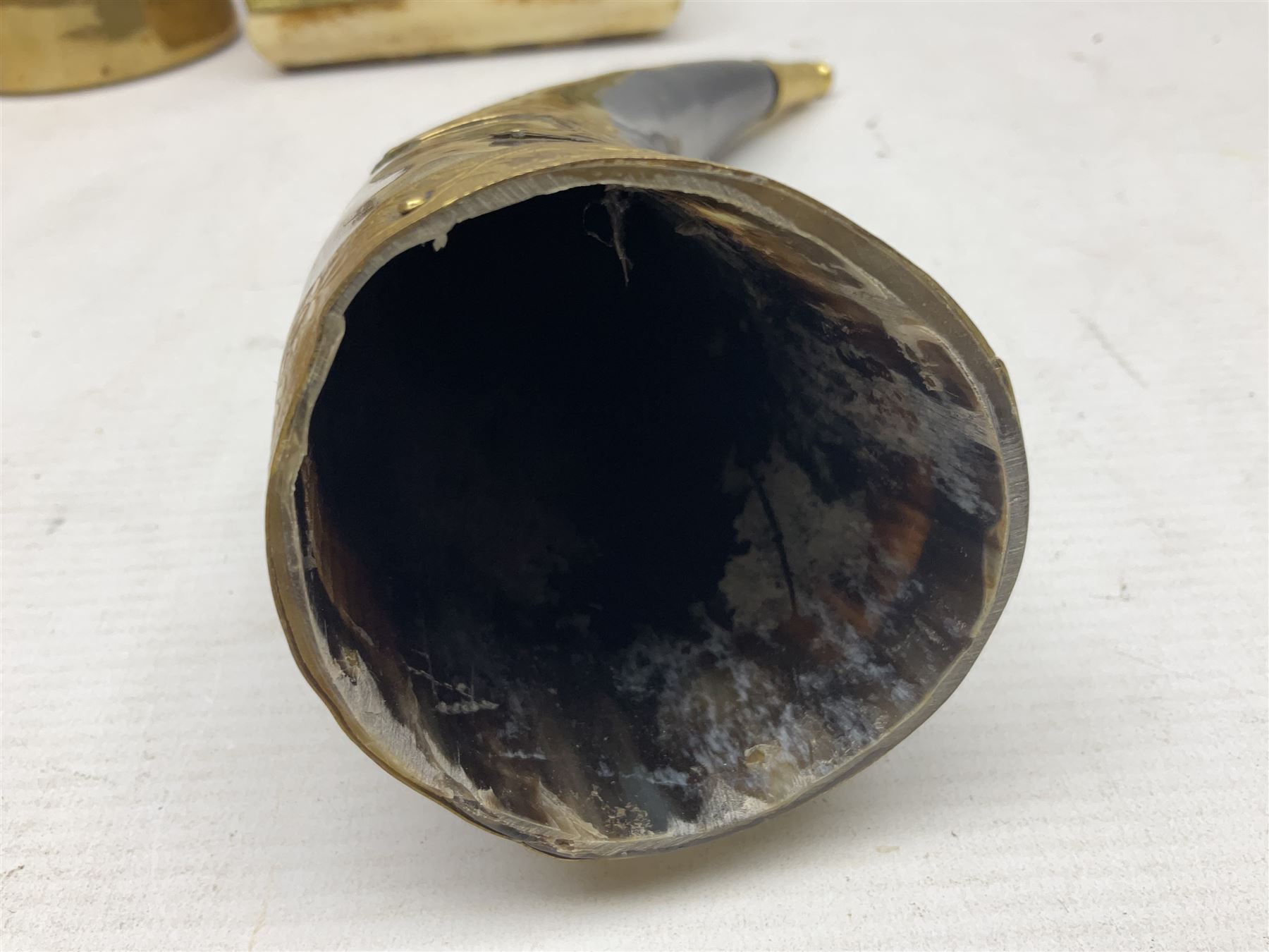 Swiss mountain hunters tobacco pipe with a horn mouthpiece, metal hinged pierced lid and brass chain, the black coated body adorned with small metal cow flowers, together with two other pipes and case, brass mounted horn, brass mounted bone box, carved mother of pearl handled knife and fork and brass jug