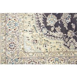 Central Persian Nain hand-knotted carpet, indigo field with central cusped medallion of radiating palmette form, enclosed with an elongated cartouche issuing network of scrolling vine work, arabesques and flowering sprays, surrounding ivory field of conforming design filled with foliate motifs and palmettes, spandrels of complimentary design with angular reserves, within principal border of ivory ground with scrolling vinery rosettes and arabesques, flanked by narrow guard stripes, with cotton fringe ends 