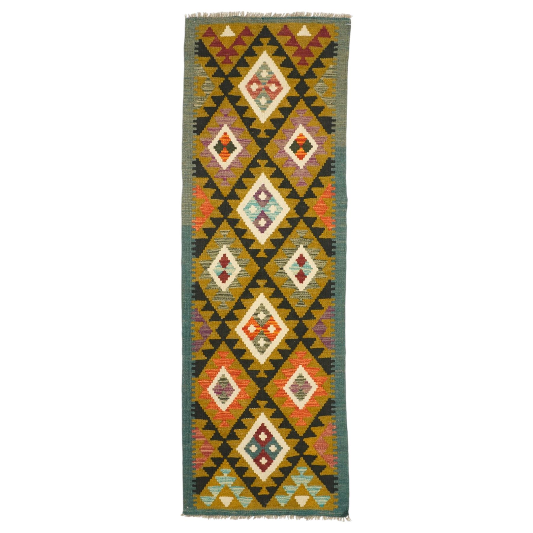 Afghan Maimana flatweave kilim runner, central field features large bold nested diamond motifs and stylized geometric lozenge patterns on olive purple, blue, and green tone ground, dark green border stripe, with fringe ends